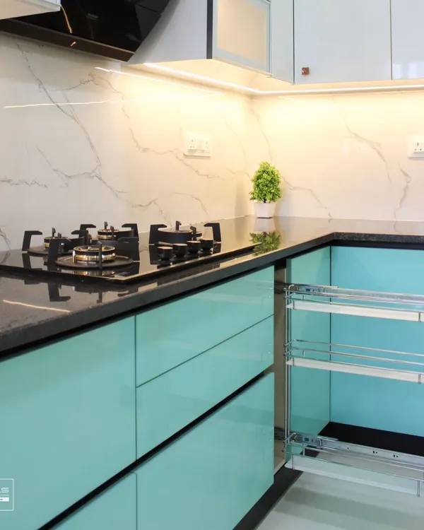 A close-up of our high-gloss turquoise kitchen, featuring a convenient pull-out spice rack next to the hob. The design is complemented by a black granite countertop and a white marble-look backsplash.