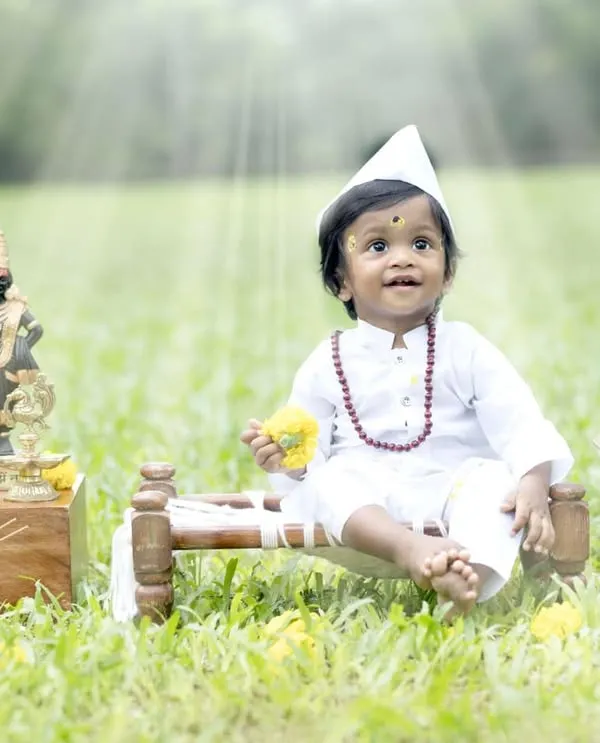 Jai Hari Vitthala. This little boy is dressed as a tiny Varkari, complete with a topi and tulsi plant, in a divine outdoor setting.