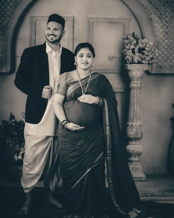 A classic couple's portrait from a vintage-themed maternity shoot. Dressed in traditional Maharashtrian attire, the couple stands proudly, creating a formal yet warm image that honors their cultural roots.