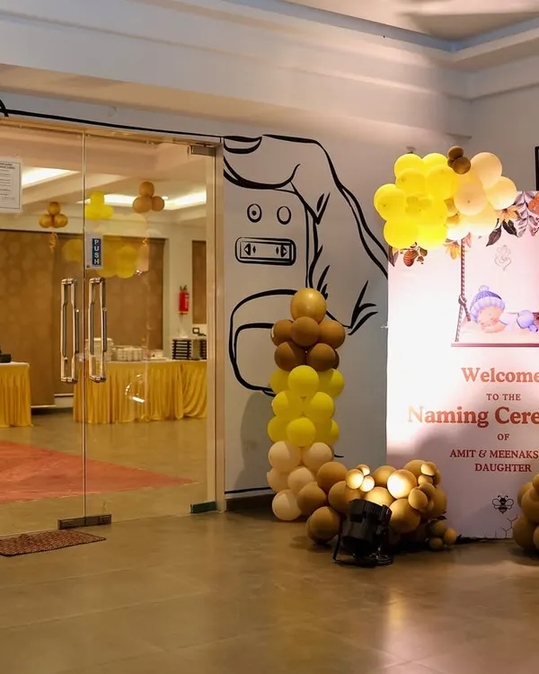 We set a welcoming tone for this naming ceremony with a custom entrance display. It features a personalized welcome sign and balloon pillars in a warm yellow and brown color scheme.
