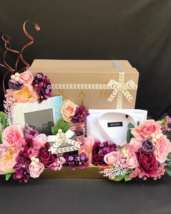 A luxurious wedding trousseau platter for the groom, featuring a designer shirt, accessories, and other gifts, all surrounded by a lavish floral arrangement. This is how you make a statement.