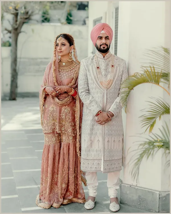A classic portrait of a Sikh couple after their Anand Karaj. Their coordinated pastel outfits and the elegant setting create a picture of grace and tradition.