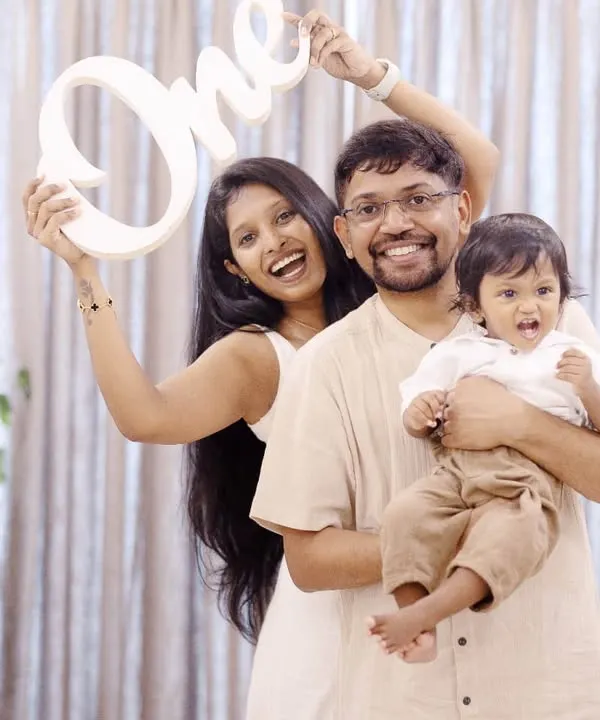 Celebrating turning one with a fun family photo. Using props like this 'One' sign adds a special touch to first birthday milestone sessions in the studio.