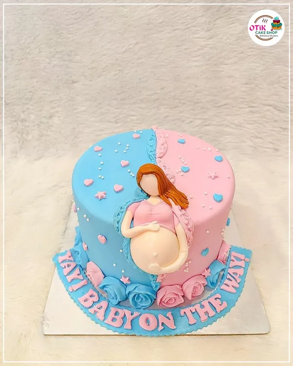 A fun "Yay! Baby on the way!" cake for a gender reveal party. The half-pink, half-blue design with a fondant pregnant belly is a creative way to build excitement.