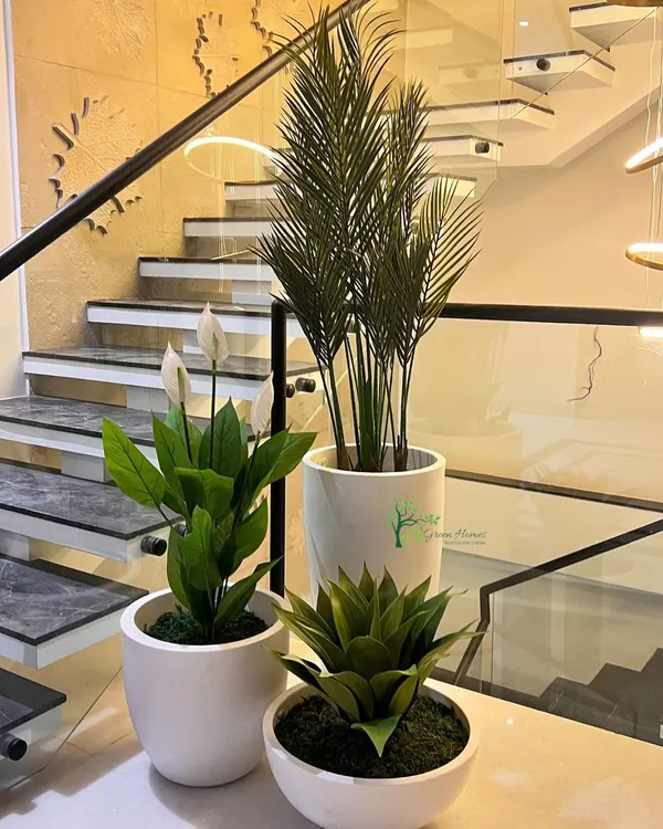 A curated cluster of faux plants in modern white ceramic planters. We offer arrangements like this featuring artificial peace lilies, palms, and succulents to add a touch of green to any corner or tabletop.