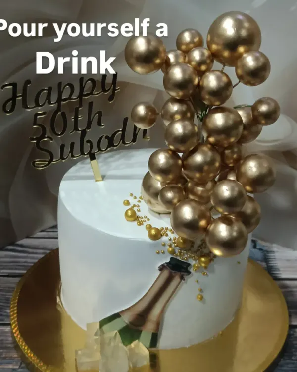 A fun and celebratory cake for a 50th birthday. This design features a champagne bottle popping with golden spheres, creating a sense of bubbly excitement.