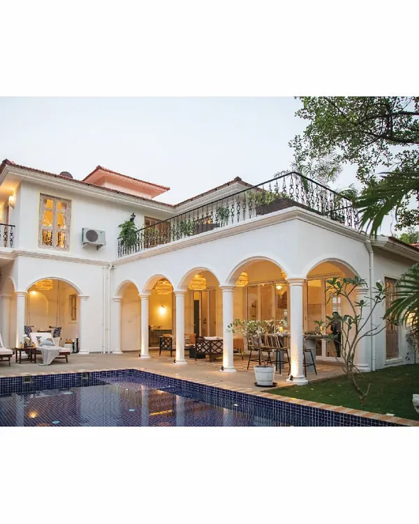 The exterior of our 'Sand Tales' villa in Goa, a home designed for peace and solace. The classic architecture with arches and a terrace overlooks a private pool, creating a seamless connection between the indoor and outdoor living spaces. It's a true escape from the madness of a fast-paced city.