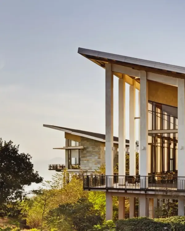 The Club Mahindra Tungi Resort, a lakeside retreat designed to be shaped by its landscape. The structure sits quietly overlooking Pawna Lake, with angled roofs and expansive windows that draw the scenery inward, creating a seamless connection between the built form and the natural terrain.