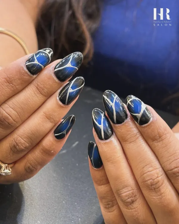 A bold and graphic design for a modern look. We combined a deep blue cat-eye effect with sharp, silver geometric lines over a black base to create this striking and futuristic nail art.