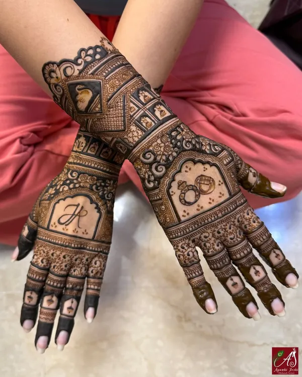An elegant engagement mehendi featuring the couple's initial, intertwined rings, and a portrait of the bride. It's a beautiful way to celebrate the start of a new journey.