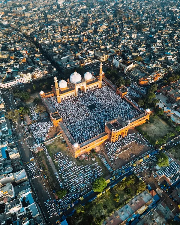 This wide aerial shot of Jama Masjid shows the historic mosque surrounded by the dense cityscape of Old Delhi during Eid. It captures the context of the gathering, showing how faith is woven into the fabric of the city.