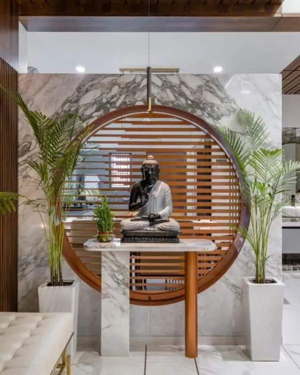 A tranquil and elegant space for meditation or prayer. We created a focal point with a large Buddha statue on a marble-topped table, set against a circular wooden frame with slats that filter light beautifully.