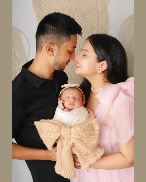 A beautiful, intimate moment between new parents and their baby. The mother's happy smile and the father's gentle gaze create a portrait filled with love and warmth.