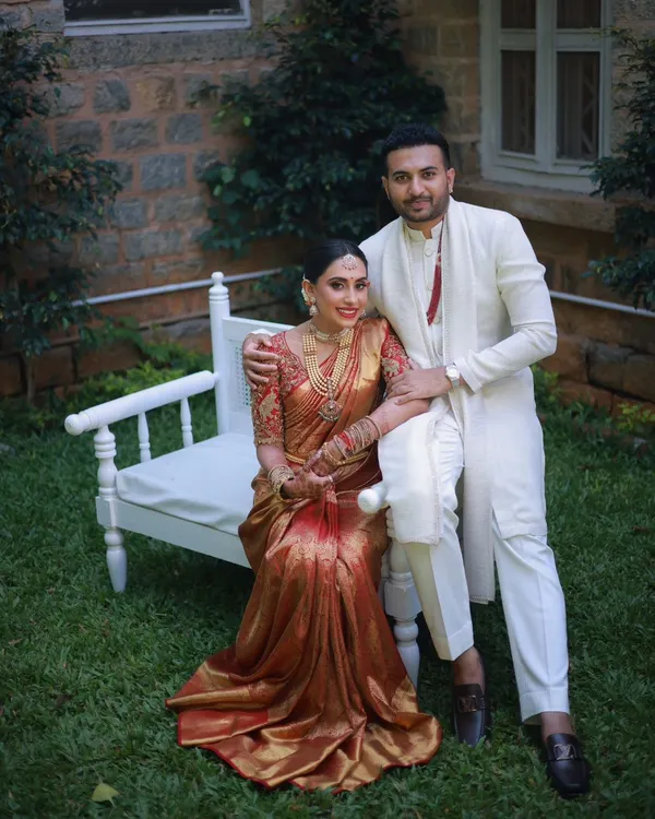 A beautiful portrait of the bride and groom. Her traditional muhurtham makeup features a warm, golden glow and a classic red lip, perfectly harmonizing with her red and gold silk saree.
