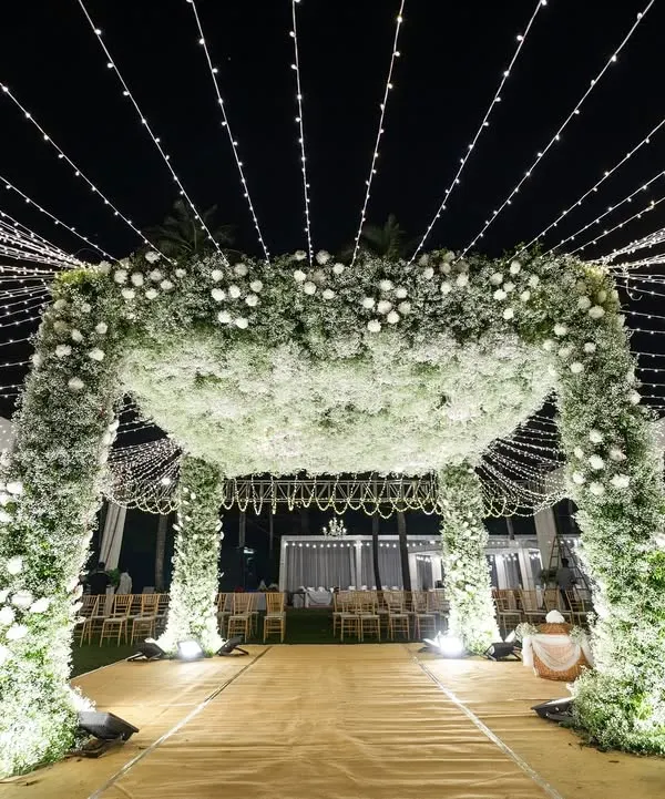 We brought a starry night sky indoors for this unforgettable reception. This magnificent octagon mandap, enveloped in nearly 500 bunches of fresh baby's breath, stands as a testament to ethereal romance. A canopy of twinkling fairy lights and elegant crystal chandeliers casts a magical glow, creating a truly dreamlike world for the couple and their guests.