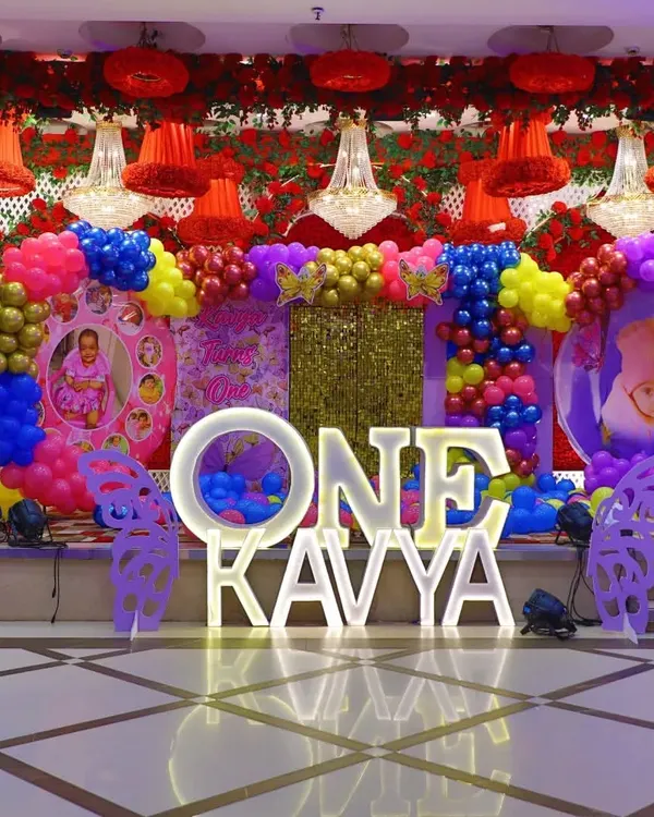 This is the kind of grand, colorful stage I love to create for a first birthday. For Kavya's big day, we used a vibrant butterfly theme with bold colors, a sparkling gold backdrop, and large light-up letters to make the celebration feel truly special in a large banquet hall.