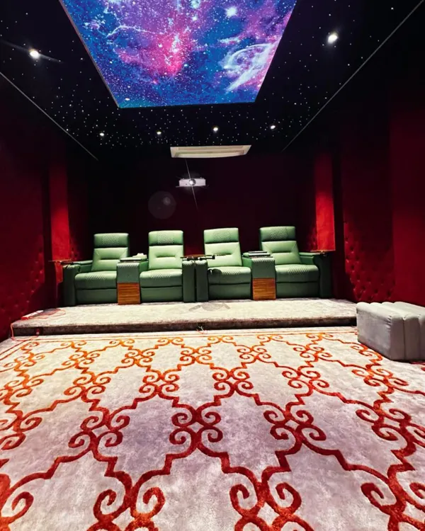 A full view of a private cinema we designed, showcasing the custom patterned carpet, elevated platform for optimal viewing angles, and the stunning galaxy-effect ceiling. Every element is chosen to enhance the cinematic feel.