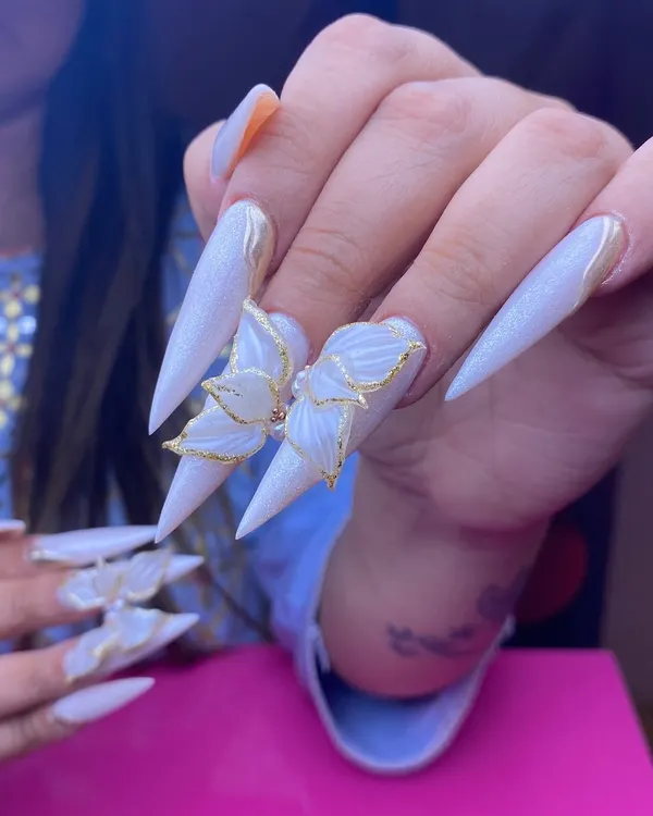 An ethereal bridal look featuring extremely long, pearly-white stiletto extensions adorned with delicate, gold-lined 3D butterfly wings. This is the kind of statement art I create for a truly memorable wedding day.