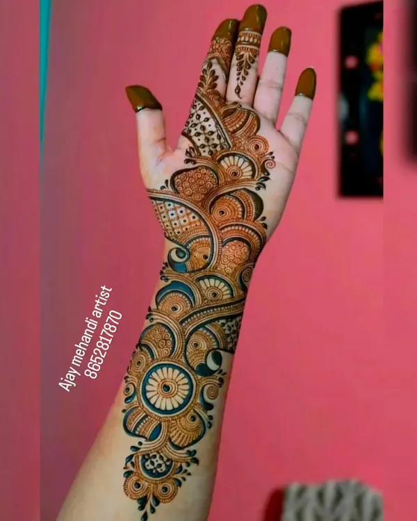 A beautiful Arabic mehndi design that flows elegantly from the fingers up the arm, featuring bold circular and floral patterns.