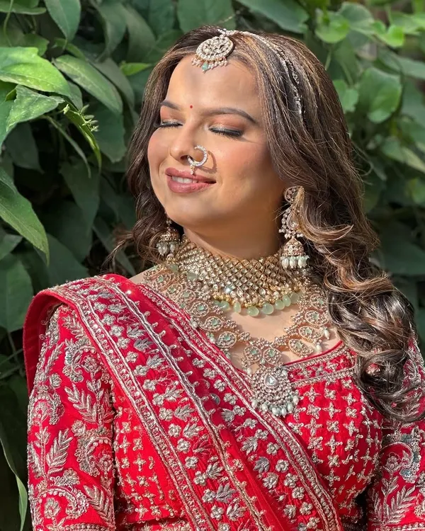 This is the complete bridal look you dream of. This stunning layered polki set with a delicate nath and maang tikka perfectly complements a traditional red wedding lehenga.