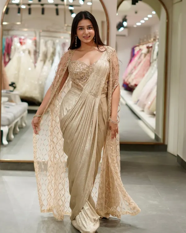 A saree that shines brighter than jewels. This golden pre-draped saree with a matching embellished cape is pure luxury and glamour.