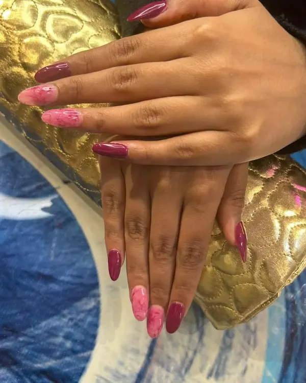 A full view of this beautiful marble nail art on long acrylic extensions. I combined solid magenta nails with accent nails featuring a hand-painted pink marble design.