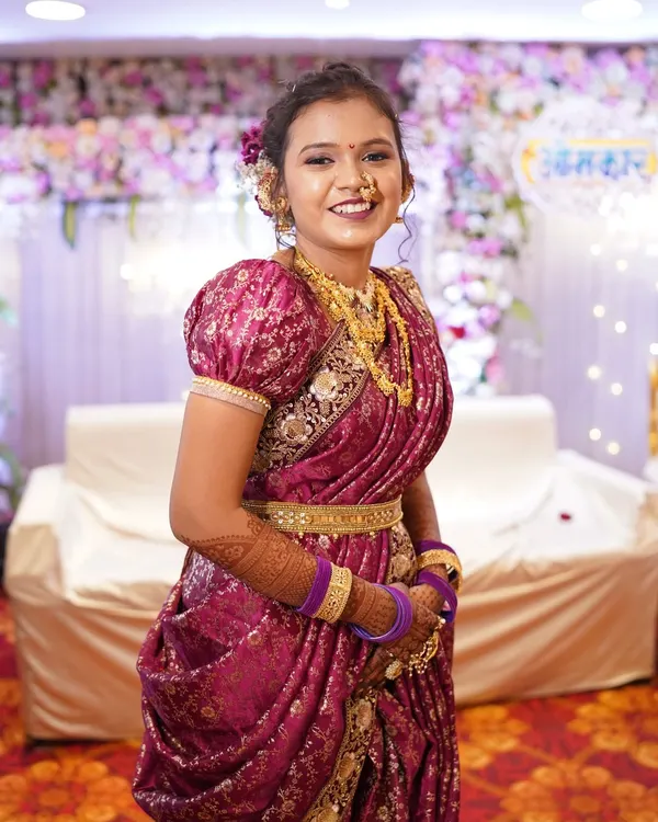 A smiling bride in a magenta Peshwai Nauvari saree. The puffed sleeves on the blouse are a classic detail for this traditional bridal outfit.