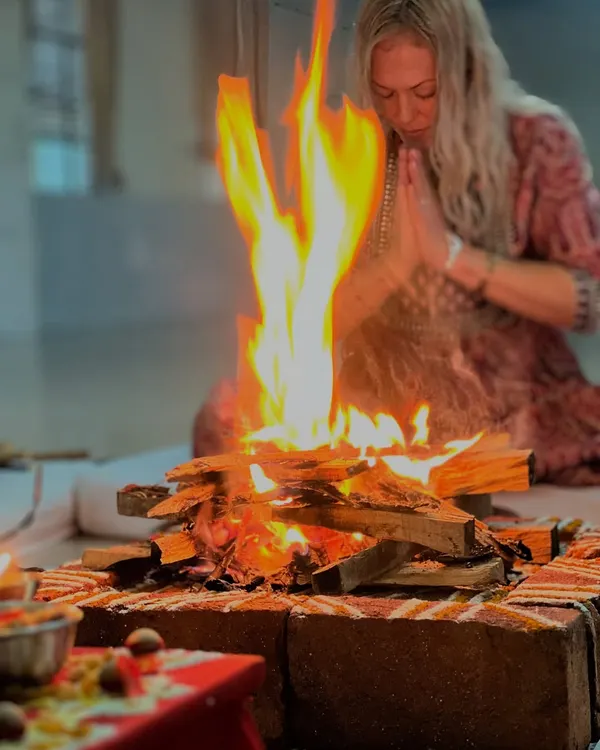 A participant offers prayers with folded hands before the sacred fire of the homam. The intensity of the flame symbolizes the burning away of impurities and the awakening of inner light.