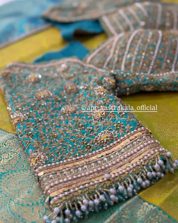 A stunning close-up of a teal bridal blouse, showcasing dense zardosi embroidery and cascading pearl beadwork for a truly opulent finish.