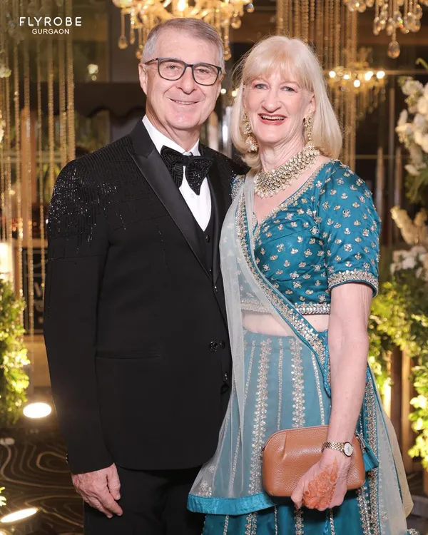 A classic and elegant look for wedding guests. This gentleman is wearing a timeless black tuxedo with a bow tie, perfectly complementing his partner's traditional attire.