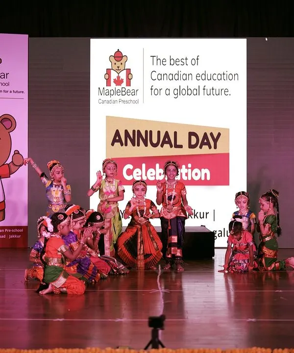 A vibrant group of young performers in traditional attire during the Maple Bear Canadian Preschool annual day. I ensure the stage is perfectly set with branded standees and professional lighting to spotlight the students.