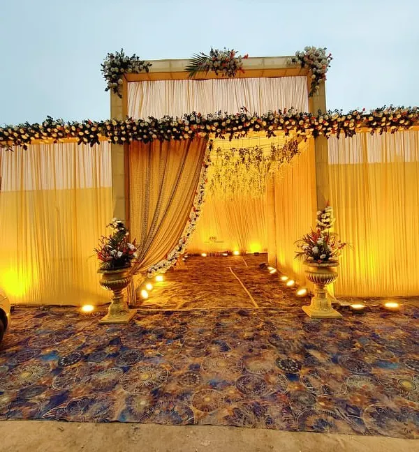 This is the kind of grand entrance I create for large wedding functions. The structure is decorated with pastel floral arrangements and elegant drapes, with warm uplighting to create a welcoming passage for guests arriving in the evening.