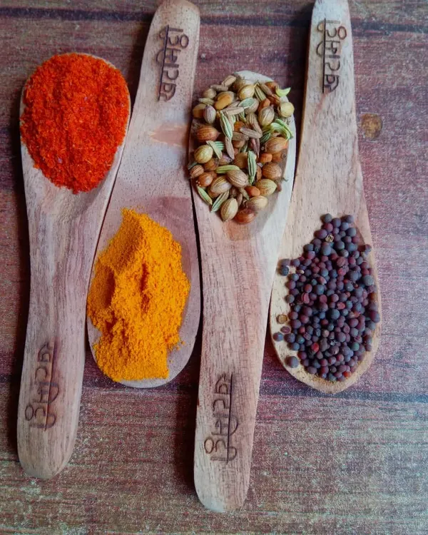 This is what purity looks like. My range of hand-pounded `masale`, including fiery red chilli, golden turmeric, and aromatic whole spices like mustard and panch phoron, all captured on our custom wooden spoons. Each spoonful is a promise of authentic flavour.