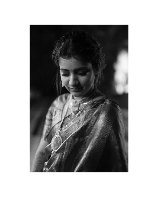 A timeless black and white portrait of the bride. Her downward glance and the soft lighting highlight the intricate details of her jewelry and the quiet grace she exudes.