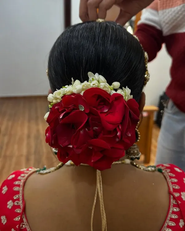 A classic bridal bun made with real red rose petals and a touch of gajra. This is a timeless hairstyle that always looks elegant.