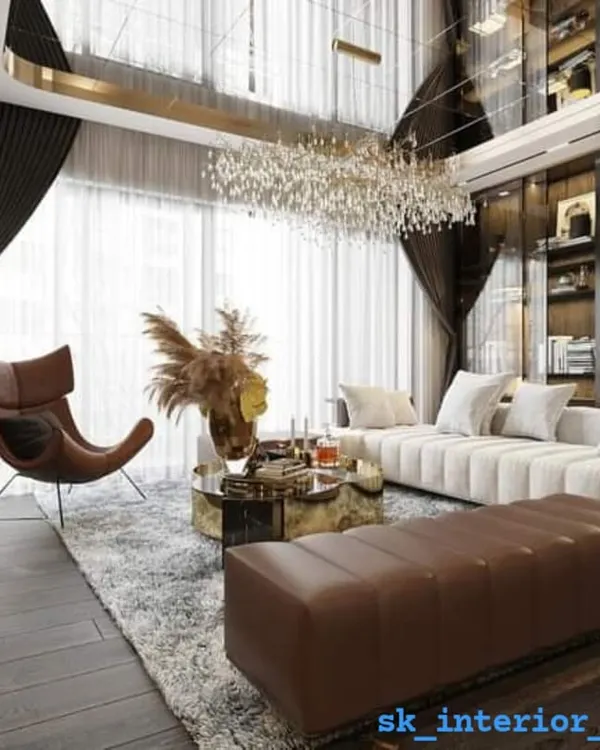 We designed this expansive living area in a duplex to feel both grand and inviting. The double-height ceiling with a magnificent crystal chandelier creates an immediate sense of luxury, while the floor-to-ceiling windows flood the space with natural light. The combination of a plush sectional sofa, a statement leather armchair, and rich, dark wood flooring establishes a sophisticated yet comfortable atmosphere for family and guests.