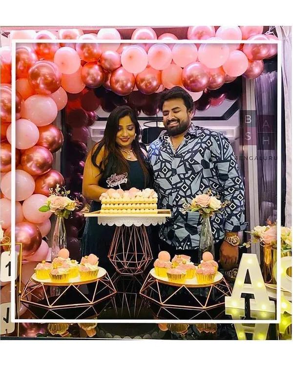 The happy couple, Anusha and Sahith, celebrating their first anniversary. They are pictured here enjoying their cake in front of the rose gold balloon arch and dessert display we created for their special day.