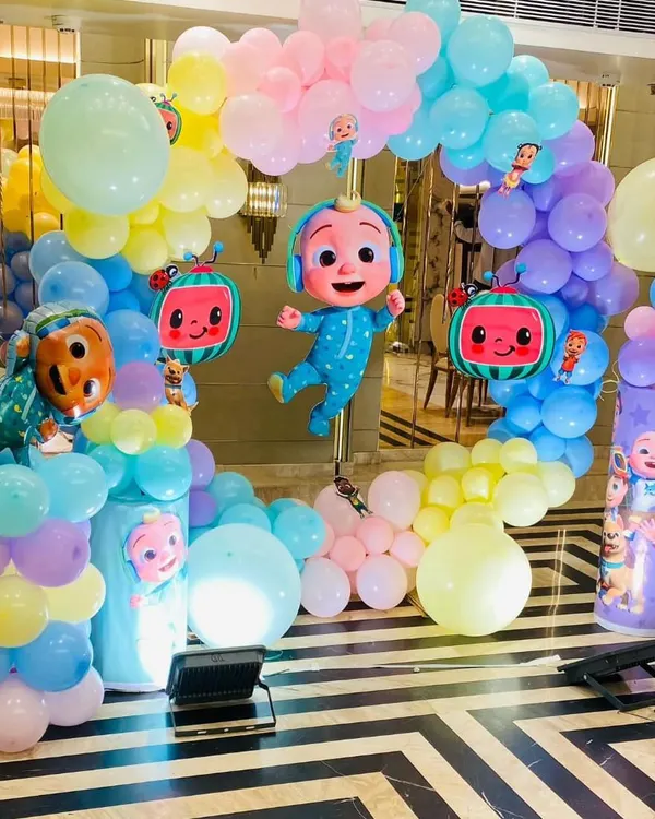 A cheerful Cocomelon themed birthday arch. This setup features JJ and watermelon character balloons amidst a rainbow of pastel balloons, perfect for a toddler's party.