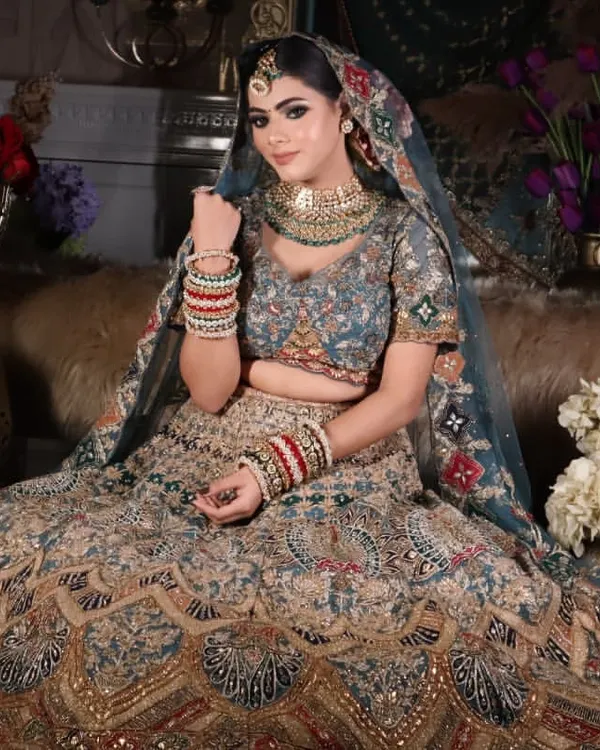 A full-length shot of a regal bridal look, showcasing the intricate lehenga and how the makeup complements the entire outfit. The focus is on creating a cohesive and grand appearance for the wedding day.