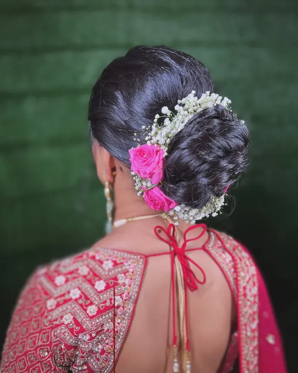 A classic bridal bun, elevated with a mix of baby's breath and delicate pink roses. This hairstyle is perfect for securing a dupatta while adding a touch of romance.