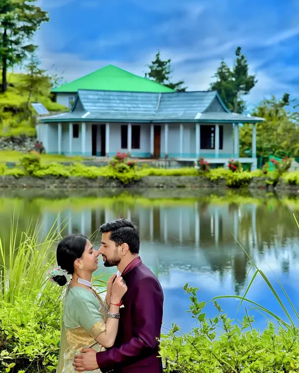 A quiet moment for a couple during their pre-wedding shoot, with a traditional Himachali house reflecting in the water. This is the kind of magic we can create in the mountains, finding serene spots that make your story unique.