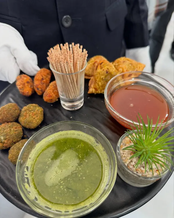 A platter of our classic Indian fried appetizers, served by our white-gloved staff. This selection includes assorted veg cutlets and samosas, paired with traditional green chutney and sweet tamarind chutney.