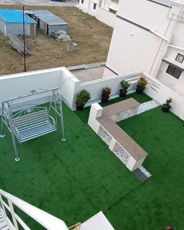 An aerial view of a terrace transformed with artificial grass. I also installed a custom L-shaped bench and a swing, creating a complete outdoor lounge area.