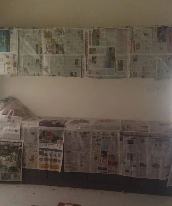 Before we begin painting, we ensure all surfaces are fully protected. Here, kitchen counters and overhead cabinets are completely covered with newspaper to prevent any paint splatters.