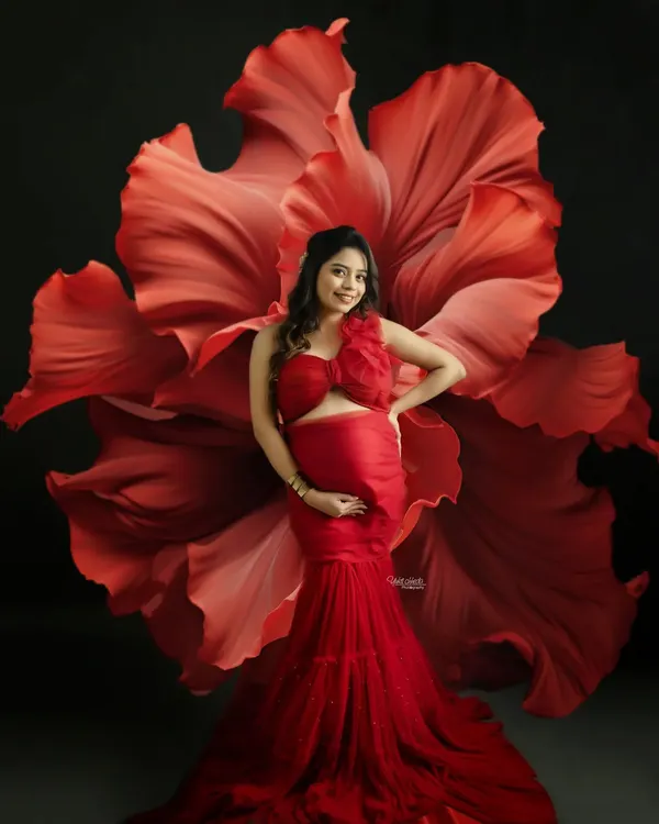 This is what I call bump beauty. I love creating dramatic, fine-art portraits that celebrate you. With a stunning red gown and a creative floral backdrop, we can make you feel like you're blooming.