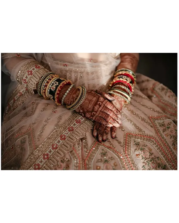A close-up on the bride's hands, showcasing her intricate bangles and mehendi, a beautiful detail of her bridal attire.
