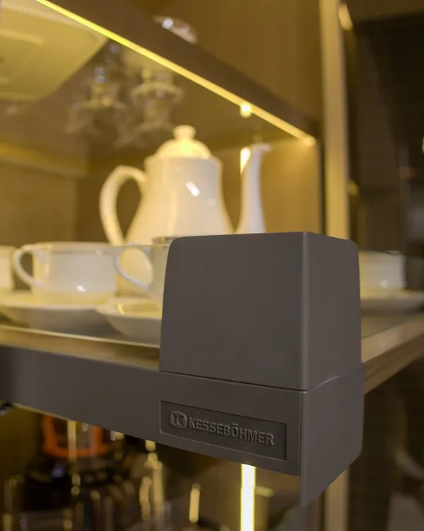 A close-up on quality hardware from Kesseböhmer, a leader in furniture fittings. This detail shot of a hinge on a glass shelf highlights our commitment to using durable, high-performance components to ensure your furniture lasts a lifetime.