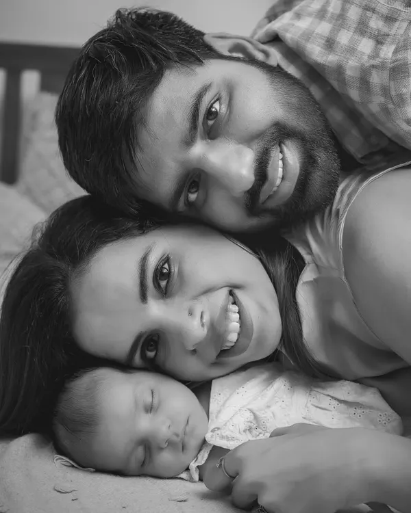 The perfect family cuddle. This black and white portrait captures the pure bliss of new parents with their sleeping baby, a moment of complete peace and love.
