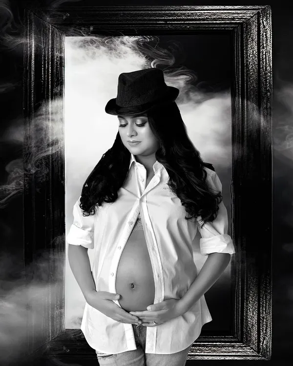 A powerful and artistic maternity portrait. This editorial style uses dramatic lighting, props, and a monochrome finish to create a striking image that celebrates the mother's strength.