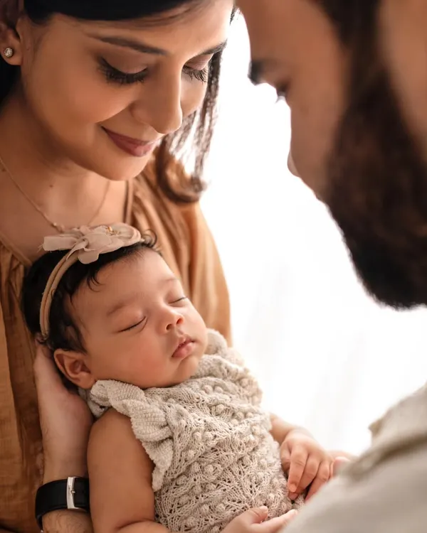 A different angle from a newborn family session, focusing on the parents' loving gaze upon their sleeping baby. These soft, warm images are perfect for remembering those early days.